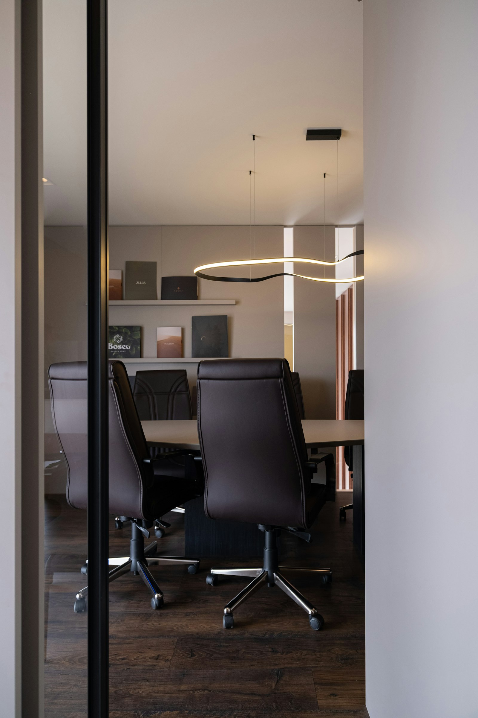 A modern boardroom with empty leather chairs under a sculptural light